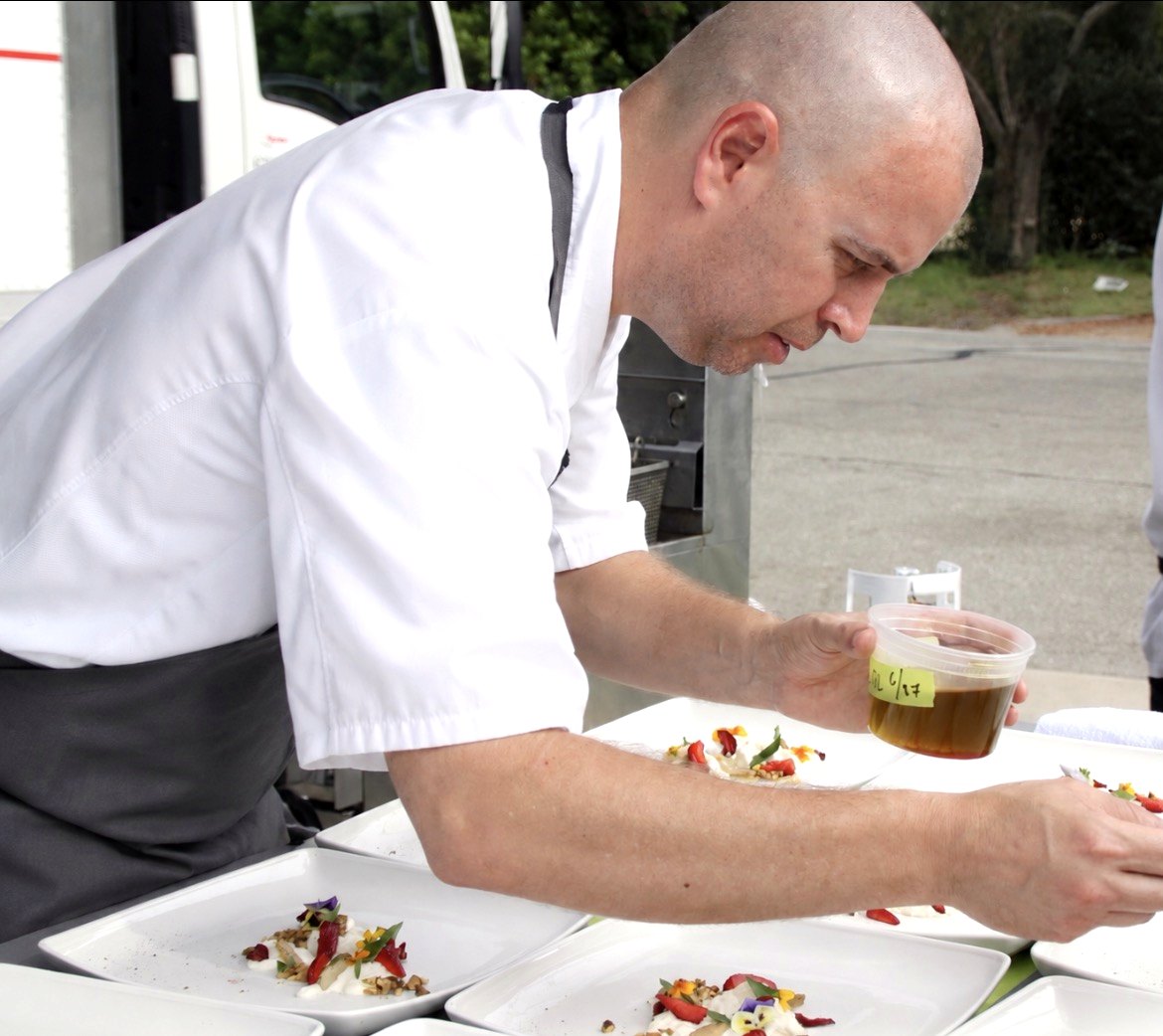 Chef tasting food from a spoon during service or prep in a professional kitchen.